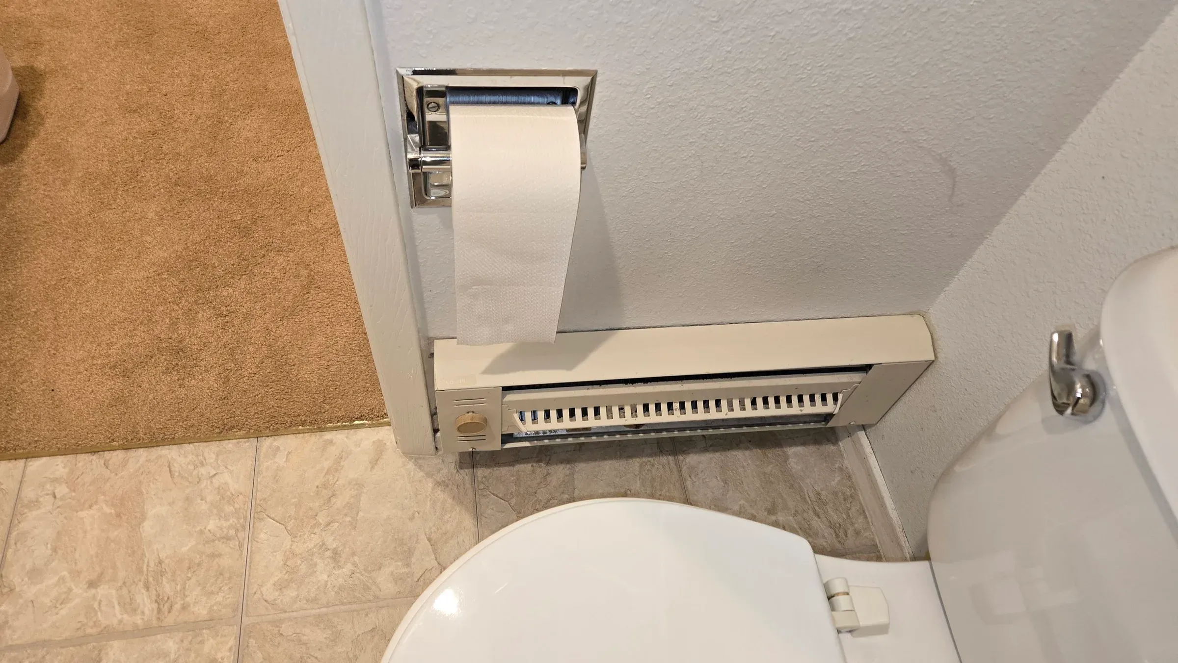 Baseboard heater with toilet paper installed above.